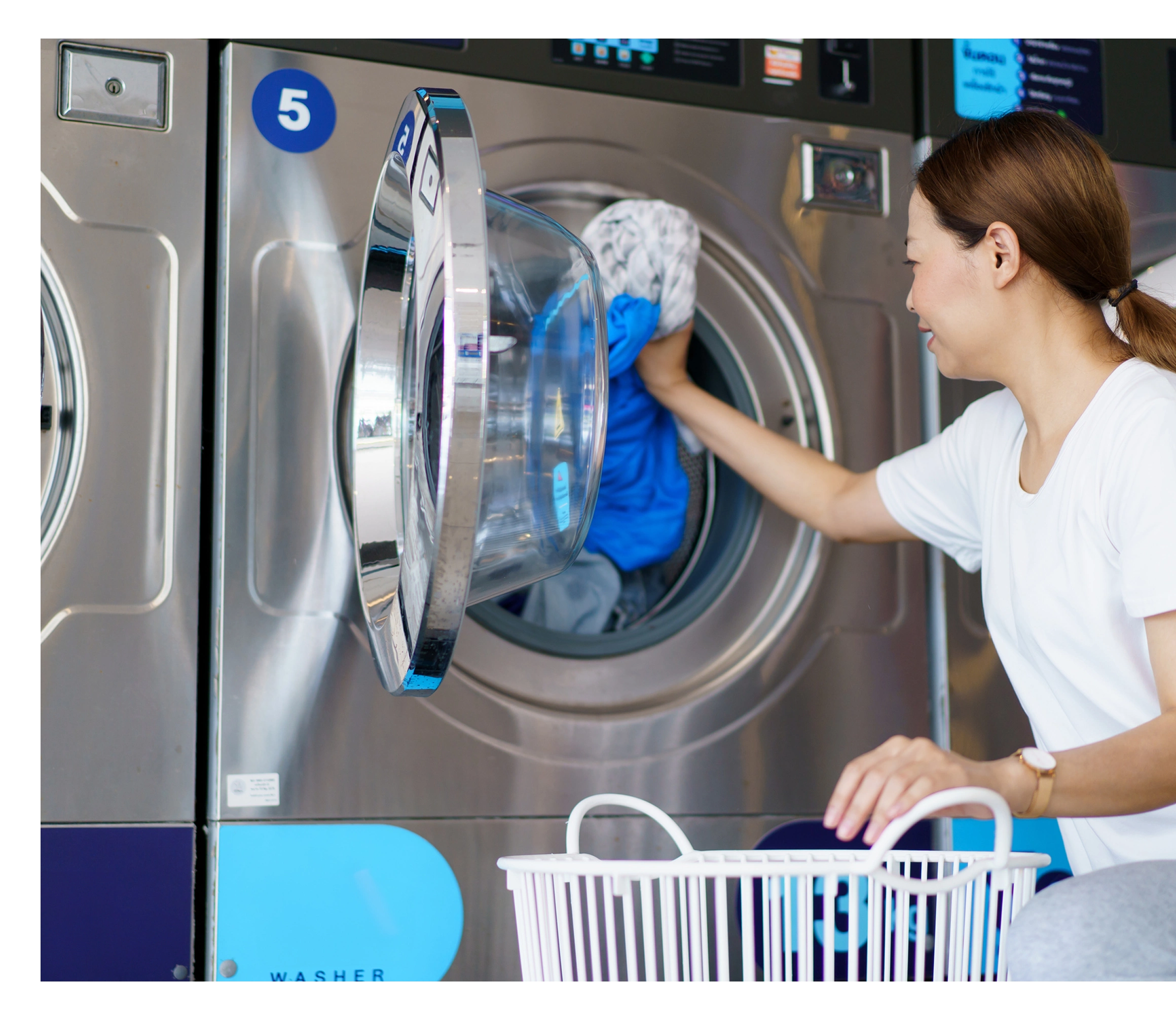 Woman loading laundry into washing machine.