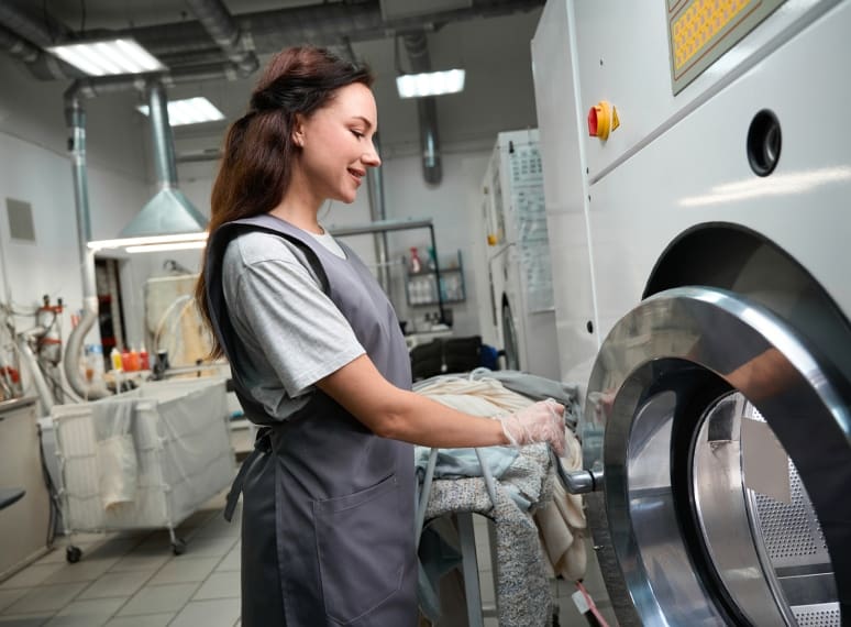 Woman operating a commercial washing machine.