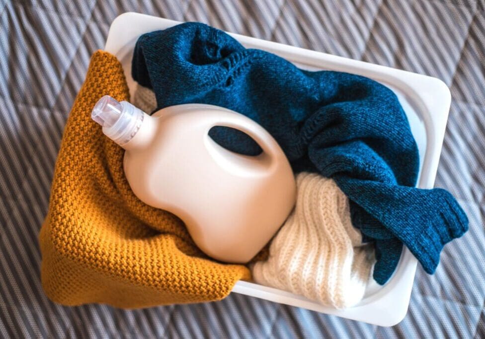 Laundry basket with clothes and detergent bottle.