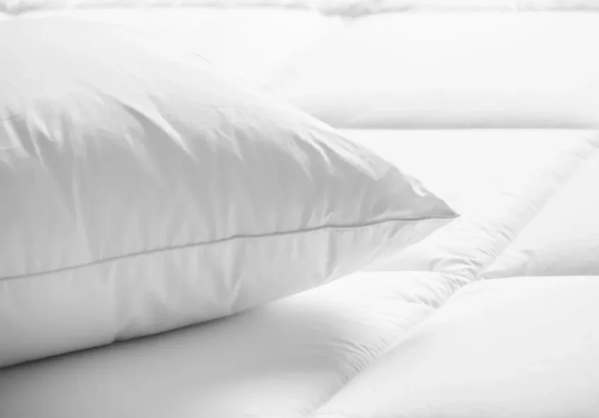 White pillow on a quilted bed.